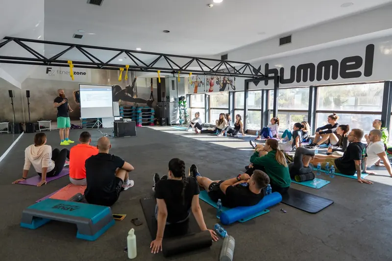 Fitness learners at a practical workshop with a presentation screen in a training hall