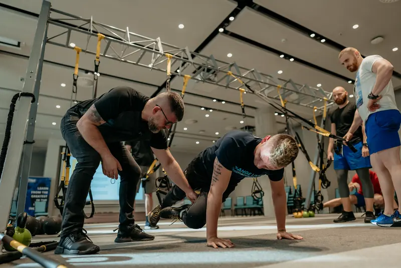 Trainers practising suspension-training exercises together in a gym